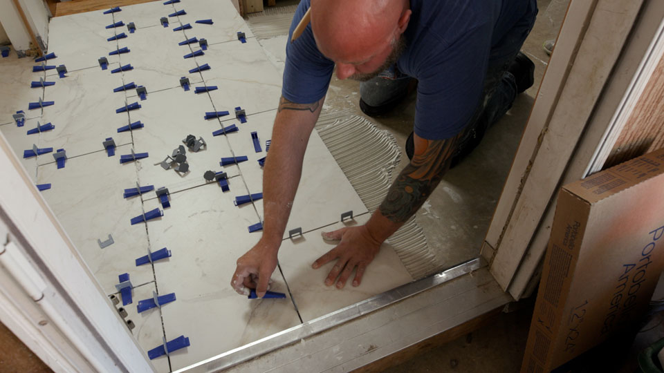 man inserting the leveling system wedge into the spacer to level the tile